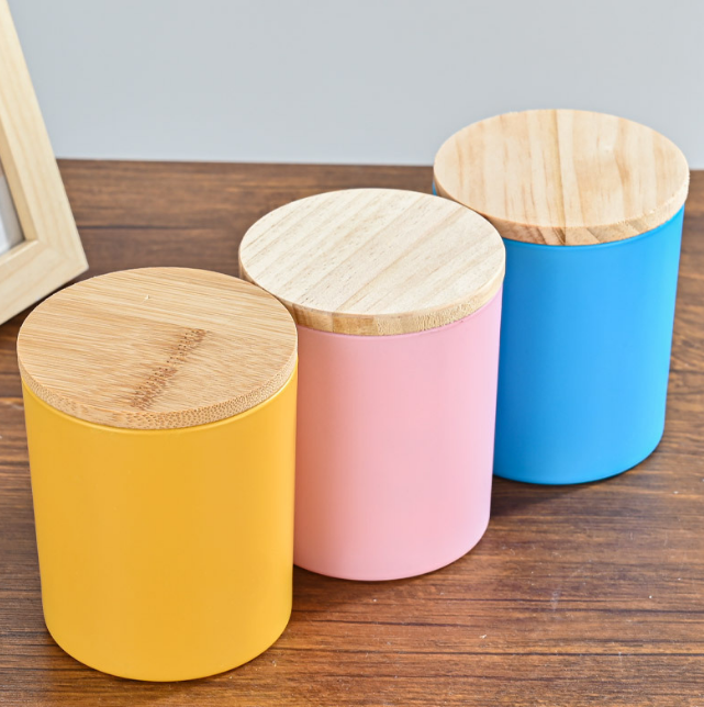 Colorful glass candle jars with wooden lids