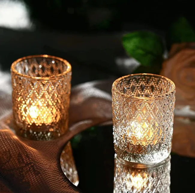 Two lit vintage embossed glass candle holders