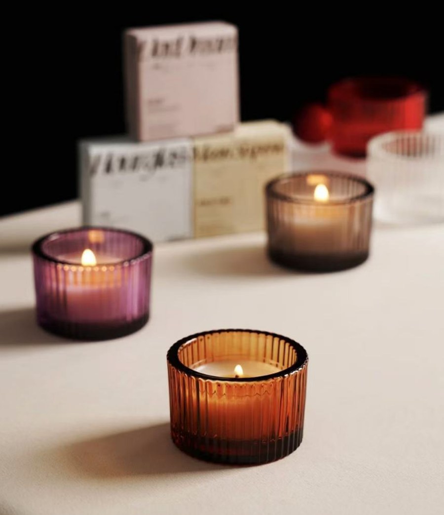 Ribbed amber glass candle holders with lit candles, purple and amber
